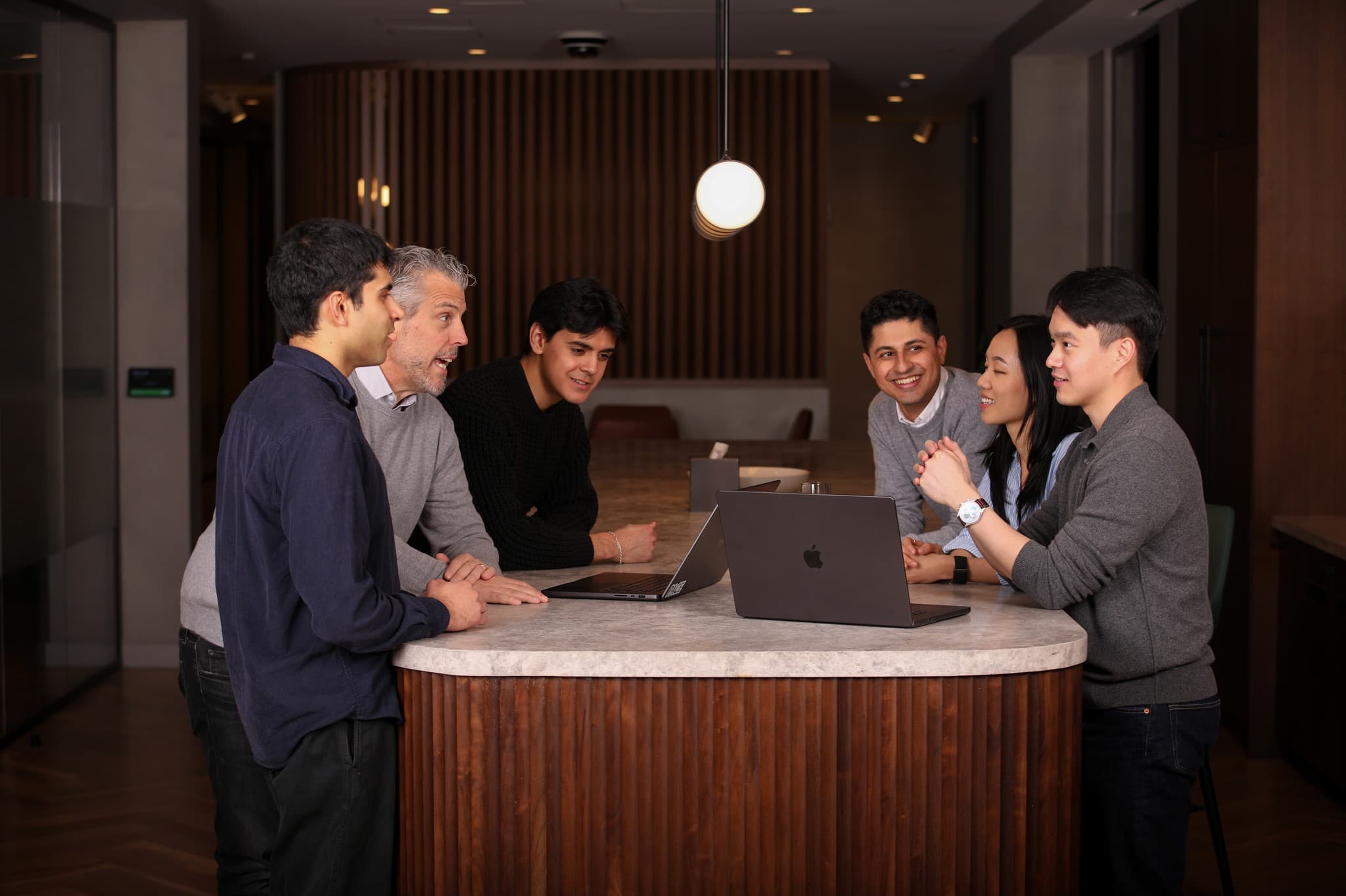 Markdown team gathered around a round meeting table with laptops in a wood-panelled office